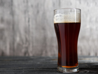 A glass of dark beer on a wooden table