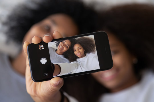 African mother daughter photographing showing selfie photo on smartphone