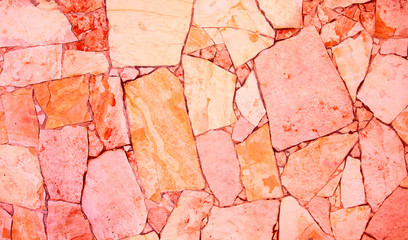 Closeup of trendy coloured living coral, orange and pink abstract sandstone mosaic wall. For...