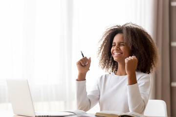 African schoolgirl sitting at desk feels happy received great news