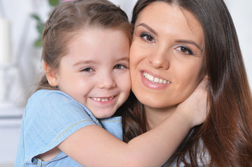 Close up portrait of little girl with mother hugging 