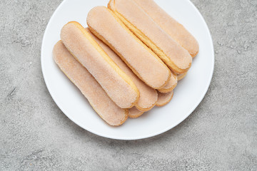 Italian Savoiardi ladyfingers Biscuits in plate on concrete backgound