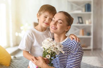 Mother receiving flowers from her cute little son at home