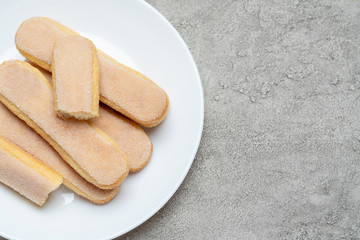 Italian Savoiardi ladyfingers Biscuits in plate on concrete backgound