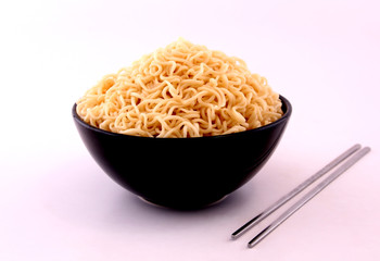 Noodles in a black bowl with a white backdrop.