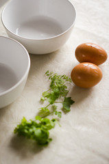 Two white cups next to two eggs and greens