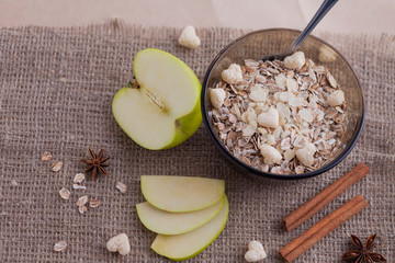 Healthy food. Muesli in a bowl on a light background with a green apple. Breakfast porridge on linen background