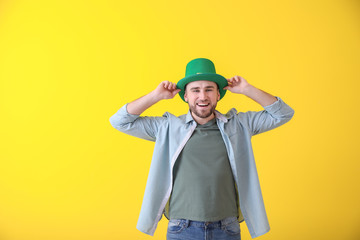 Handsome young man in green hat on color background. St. Patrick's Day celebration