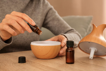 Woman filling essential oil diffuser, closeup - obrazy, fototapety, plakaty