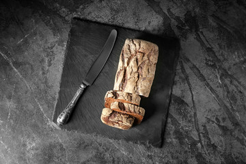 Slate plate with tasty fresh bread on grey table