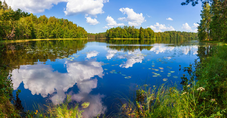 Summer day on remote calm lake in a boreal forest panorama