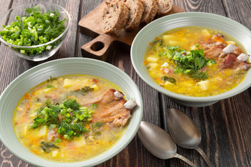 Two plates of delicious yellow split peas soup with smoked pork ribs  on a wooden table.