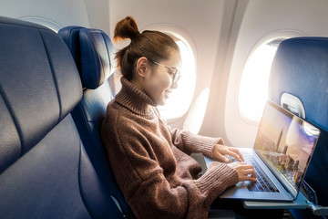 Fototapeta na wymiar Beautiful Asian woman is working with laptop in airplane