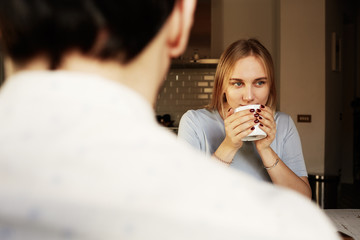 Conversation of confident man and young blond woman at home.