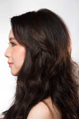 Naklejka premium Asian Woman after applying make up hair style. no retouch, fresh face with acne, eyes, cheek, nice smooth skin. Studio lighting white background, for Miss Beauty Contest Pageant, rear back side view