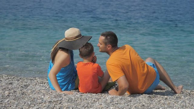 Family portrait on beach, parents kissing child in the same time, love surprise