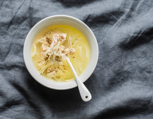 Easy chicken broth with chicken meat, onion and pepper. Soup base on a gray background, top view