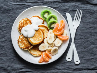 Delicious breakfast or snack - pancakes with fruit and sour cream on a grey background, top view. Baby food