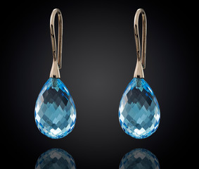 Golden earrings with gemstone isolated on black background