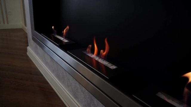 Contemporary wall mount biofuel ethanol fireplace with burning fire and decorative fireplace logs.