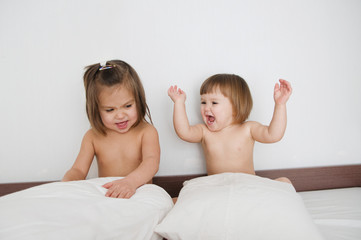 Children happy smiling sitting on bed. kids preparing to sleep. girls siblings with different age playing with pillow