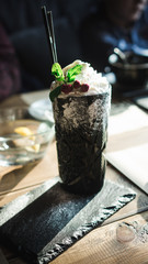 dessert of ice cream, whipped cream and berries in a tall glass decorated with a mint leaf