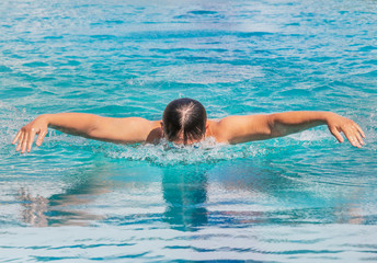 swimmer is swimming in butterfly stroke during competition in to the pool