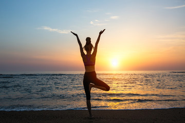Yoga woman silhouette on the sea during amazing sunset.