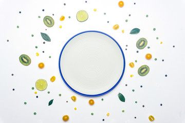 Food flat lay: spring summer concept with empty plate. Vegan vegetables and fruit detox background. Minimal flat lay concept. Kids fun food idea. Copy space.