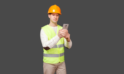 the man in a helmet with phone, in a vest looks in phone