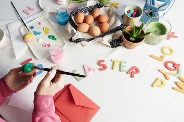 Fototapeta premium Happy easter. Young woman painting easter eggs. Happy family preparing for Easter.