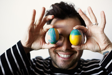 Confident man holding chicken fresh organic egg front of his face on white background. Close up