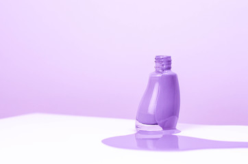 Nail polish jar spilled on a purple-white background.