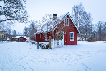 Winter scenery with red wooden house  in Sweden at dawn