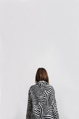 Young woman standing turned around showing her back to the camera. 
