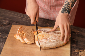 Woman cutting freshly baked bread, closeup
