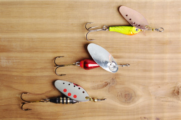 Three fishing spinners on a wooden table.