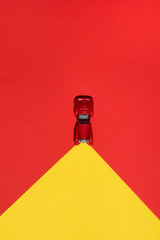 Red car is on red and yellow abstract  background with reflector on the road. Abstract conception.