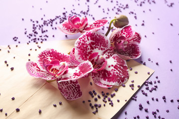 Envelope with beautiful orchid flowers on color background