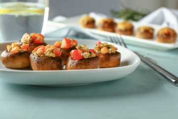 Plate with tasty stuffed mushrooms on table