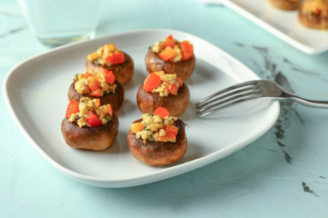 Plate with tasty stuffed mushrooms on table