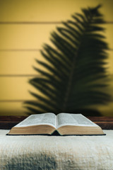 Open Holy Bible on a old  table. Beautiful yellow background. Religion concept.