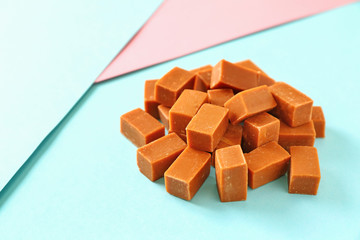 Tasty caramel candies on color background