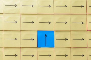 Paper sheet with arrow whose color and direction differ from those of the other ones. Concept of...