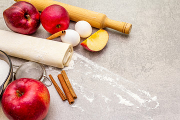 Apple pie ingredients baking concept. Fresh apples with cinnamon, flour, sugar, eggs. Cooking process on stone background, top view
