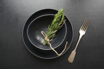 Vintage table place setting with rosemary sprig on black. Top view. Concept. Minimalism