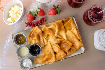 Russian traditional pancakes, blini served with jams, sour cream, and strawberry on the plate....