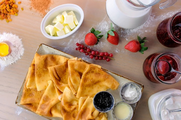 Russian traditional pancakes, blini served with jams, sour cream, and strawberry on the plate....