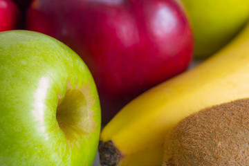 red green apples with ripe bananas and kiwi on a white background