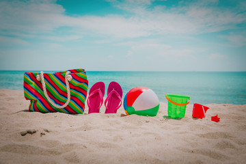 bag, flip flops and kids toys on tropical beach